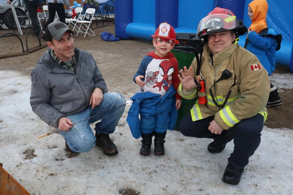 Dad, son dressed up and with face paint to look like spider man and wearing a Tiny Fire hat with a Tiny Firefighter dressed in gear