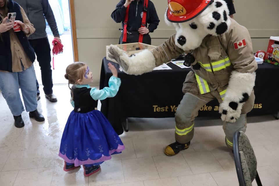 Sparky the fire dog giving a young girl dressed as Ana from Frozen a high five