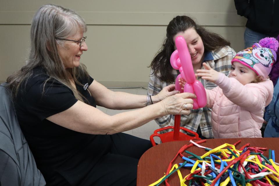 Mom and daughter receiving a bright pink balloon animal from the balloon twister