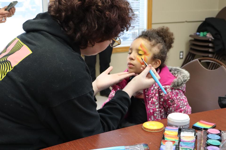 Face paint artist painting a butterfly on a young girl's face