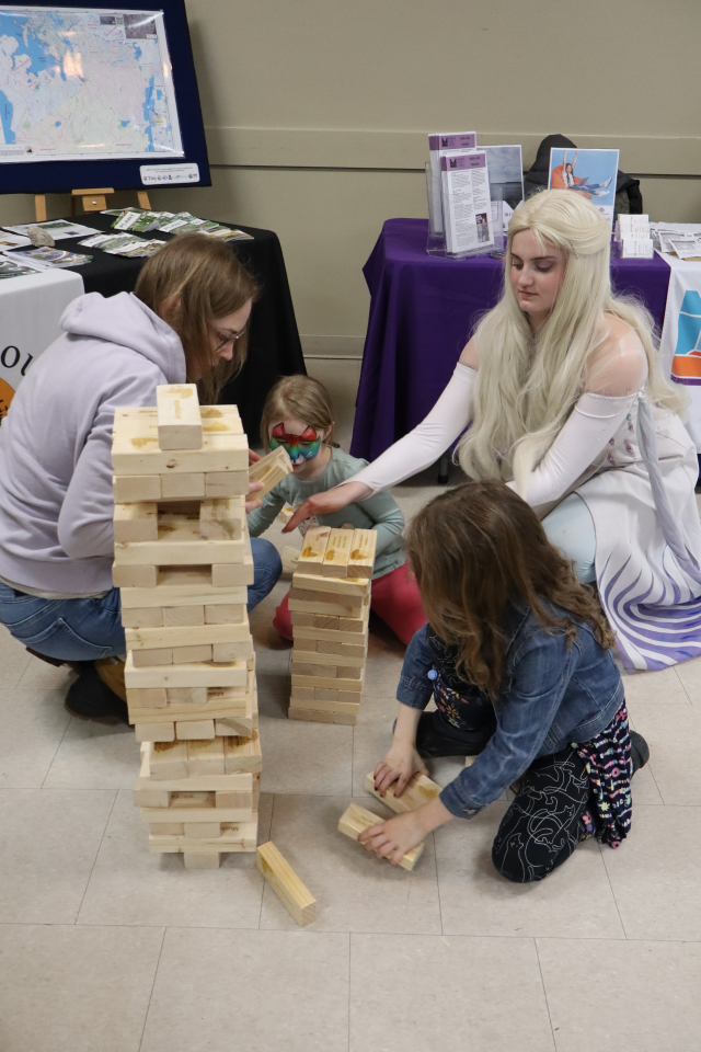 Elsa helping a mom and two young girls build the Severn Sound Environmental Association's branded block tower