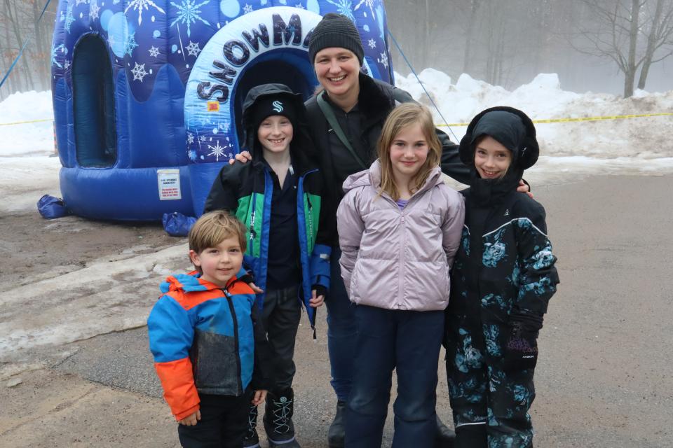 Young family posing for a photo in front of the inflatable snowman bouncy castle outdoors