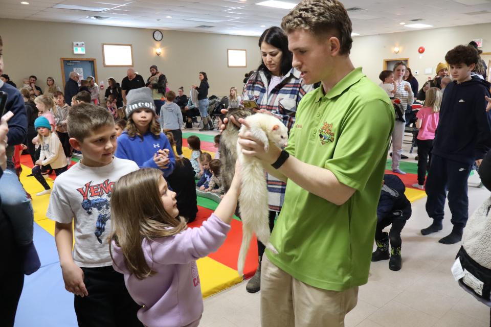 Children petting a white ferret that Zoo to You staff is holding up