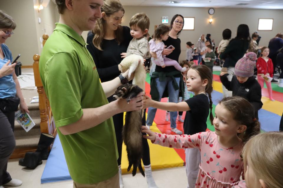 Two children petting ferrets that Zoo to You staff are holding in each hand