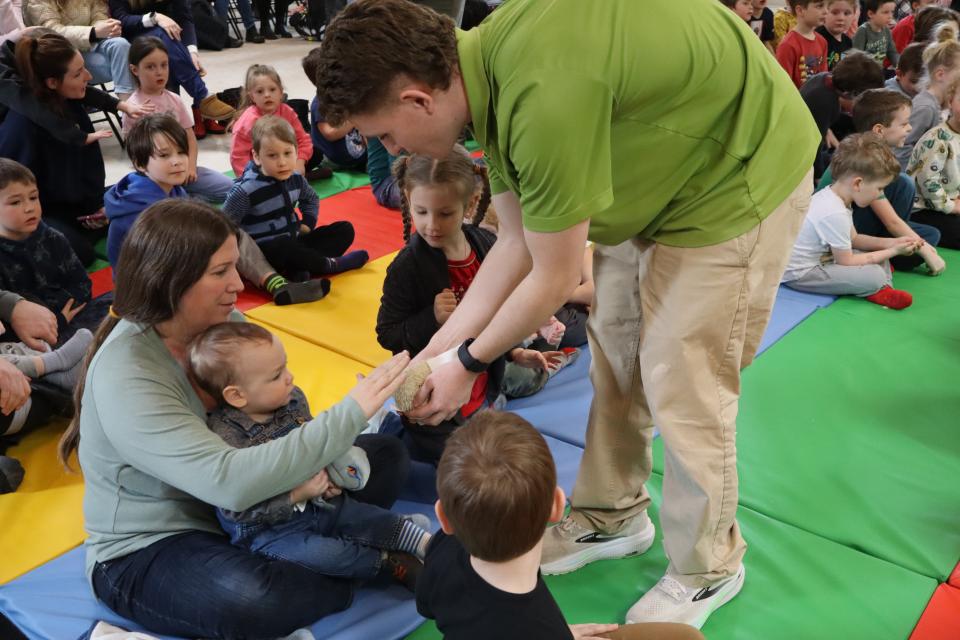 Mom and young child sitting on the colourful mats petting a hedgehog