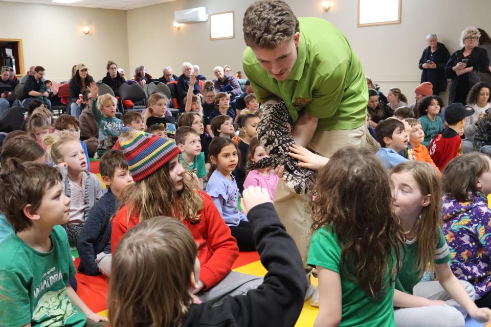 Zoo to You staff in the middle of the crowd of children with the large lizard