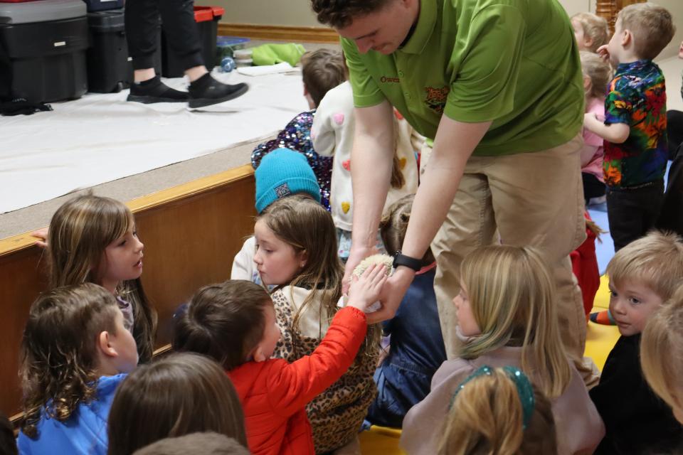 Children reaching out to pet the hedgehog Zoo to You staff is holding