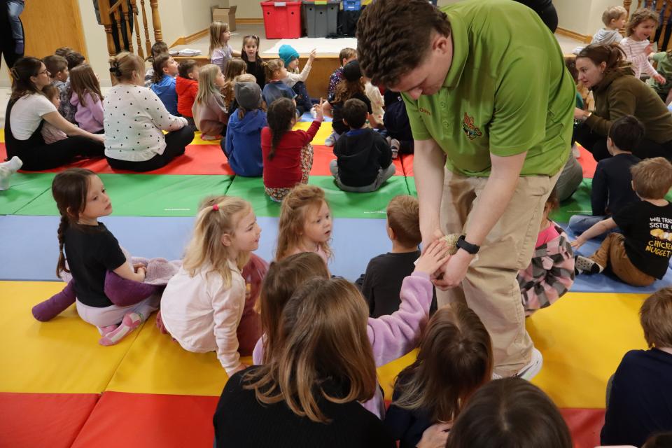 Children reaching out to pet the hedgehog Zoo to You staff is holding