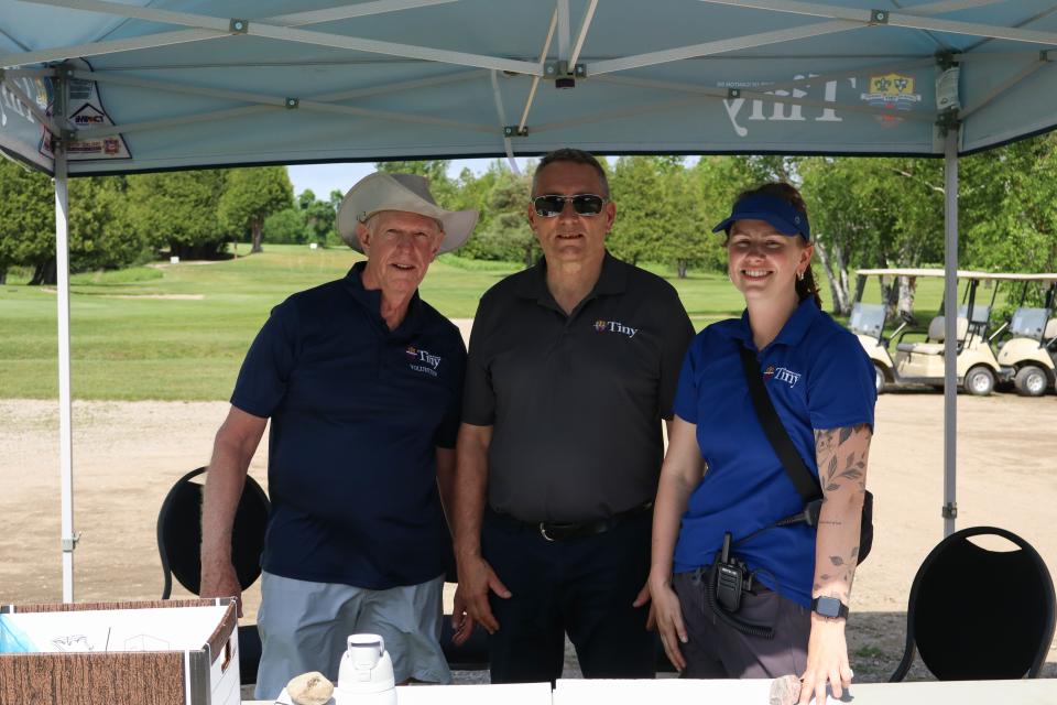 Three people standing under a Township of Tiny tent, from left to right, a volunteer, Councillor Dave Brunelle, and a staff member 