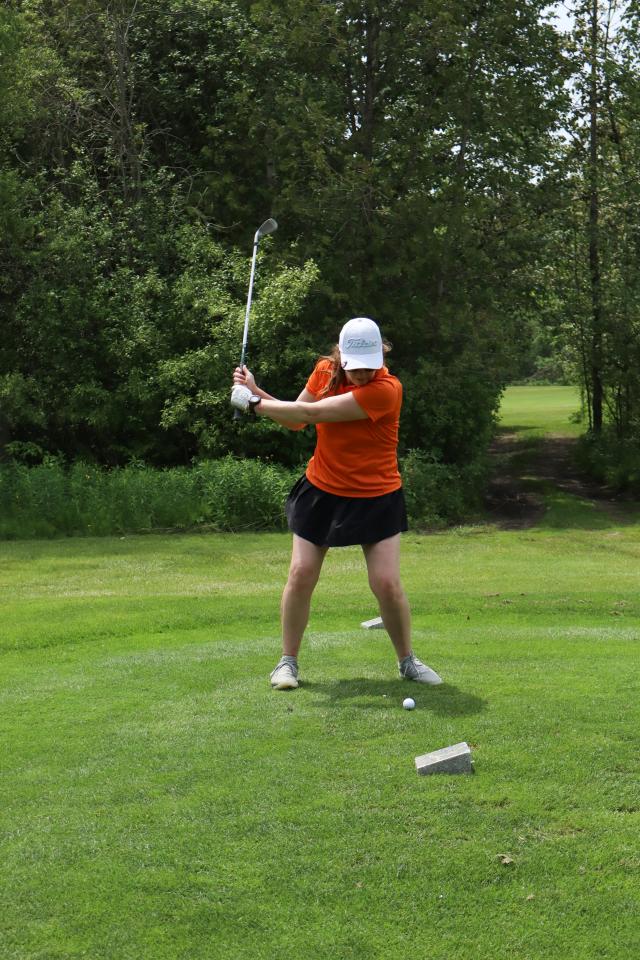 A woman lining up their golf swing