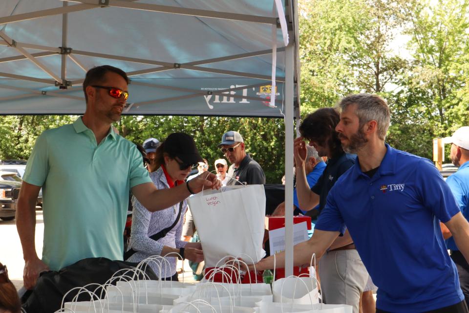 Staff handing out lunch bags to golfers at registration