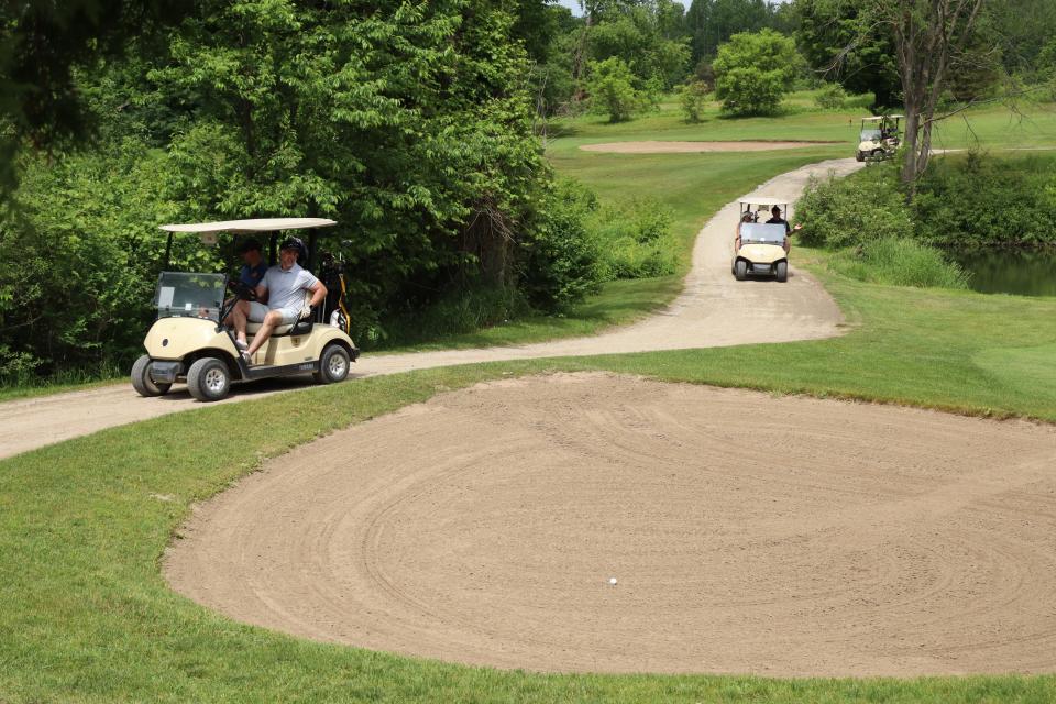 Three golf carts driving along a path out in the golf course