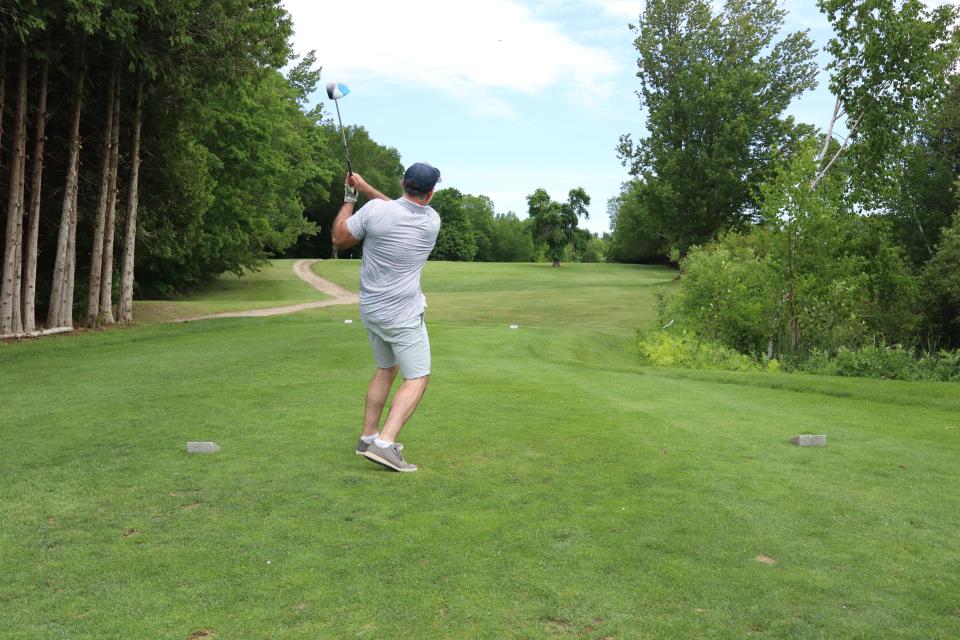 A man as their golf swing is all the way through and the golf ball is high in the sky