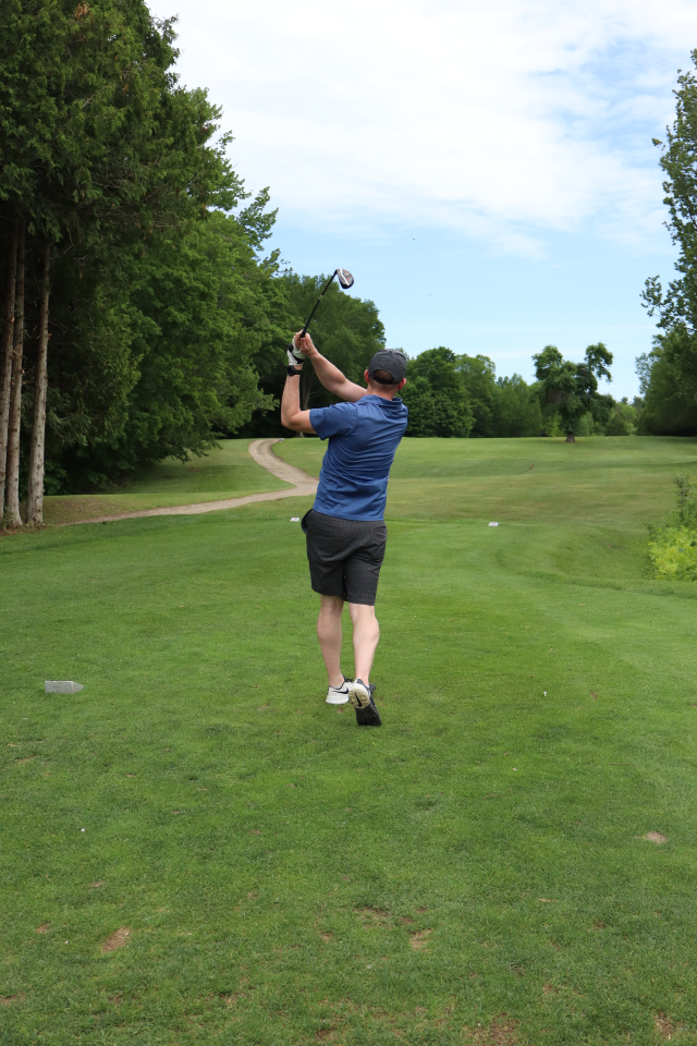 A man as their golf swing is all the way through and the golf ball is high in the sky