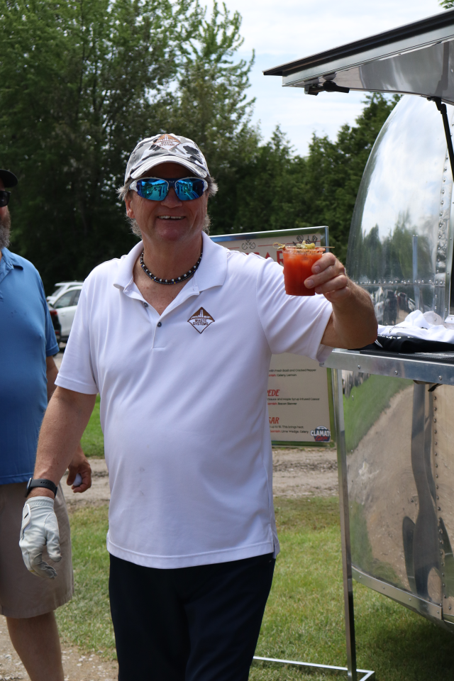 A man smiling and holding a Caesar Cocktail