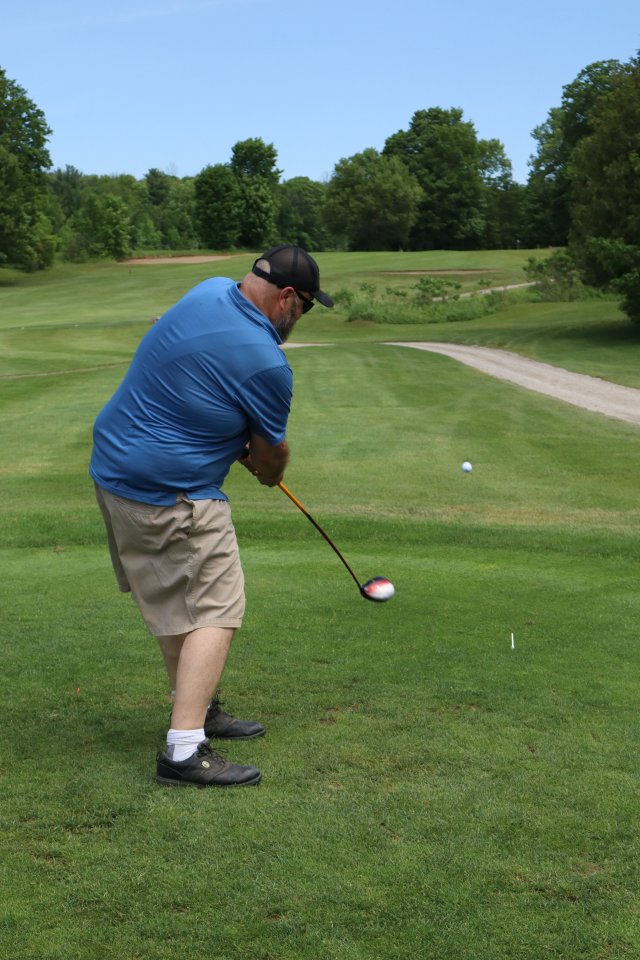 A man as their golf swing is all the way through and the ball begins to ascend off the ground