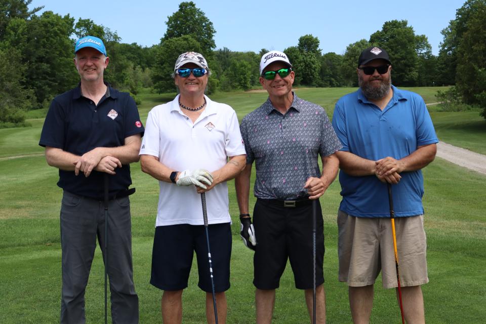 Golf foursome posing together with their golf clubs