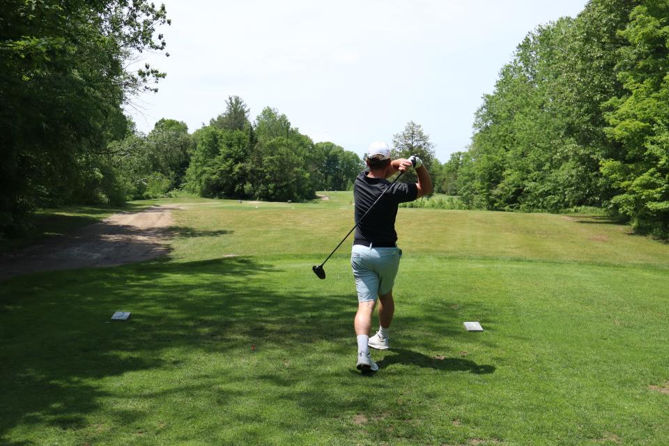 A man as their golf swing is all the way through and the golf ball is high in the sky