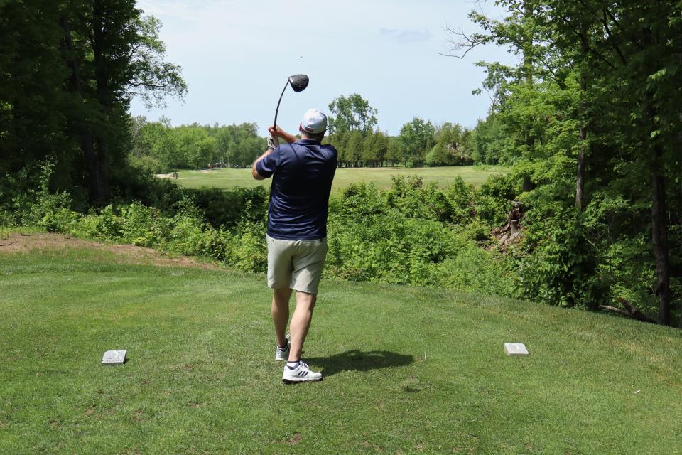 A man as their golf swing is all the way through and the golf ball is high in the sky