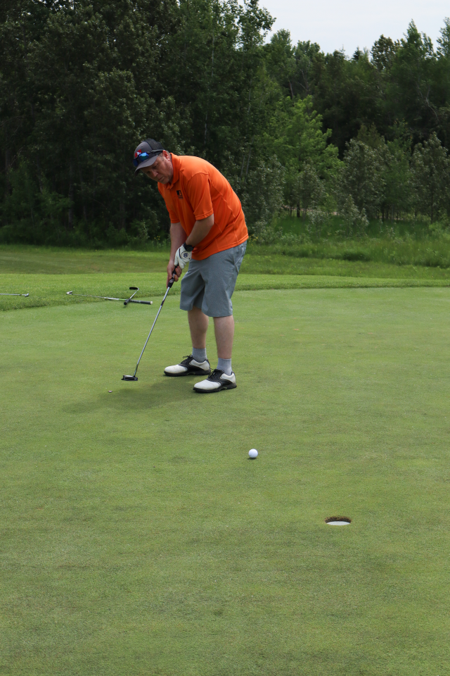 A man putting with the golf ball which is about to land in the hole