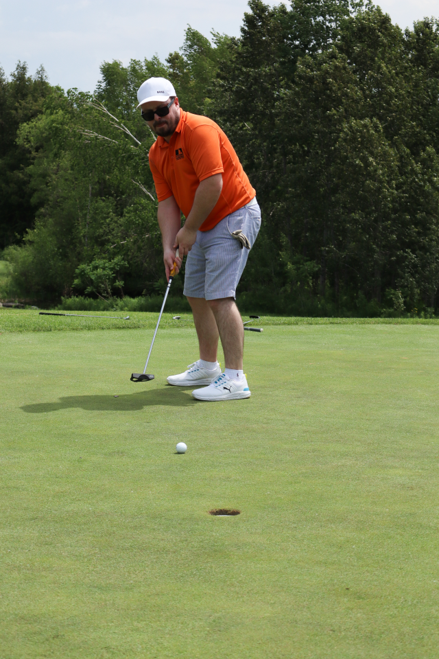 A man putting with the golf ball which is about to land in the hole