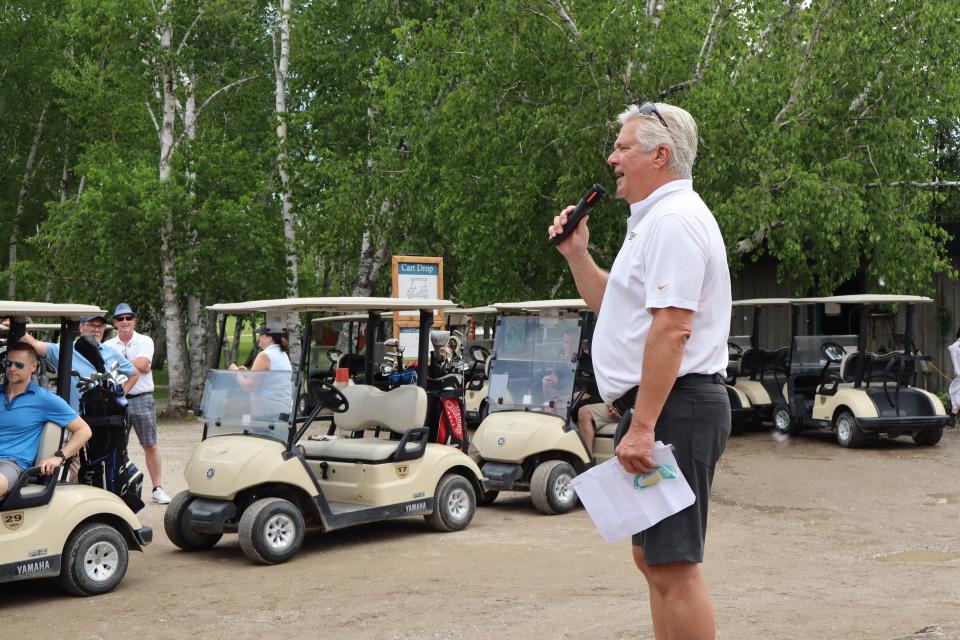 Mayor David Evans holding a microphone and addressing the golf participants