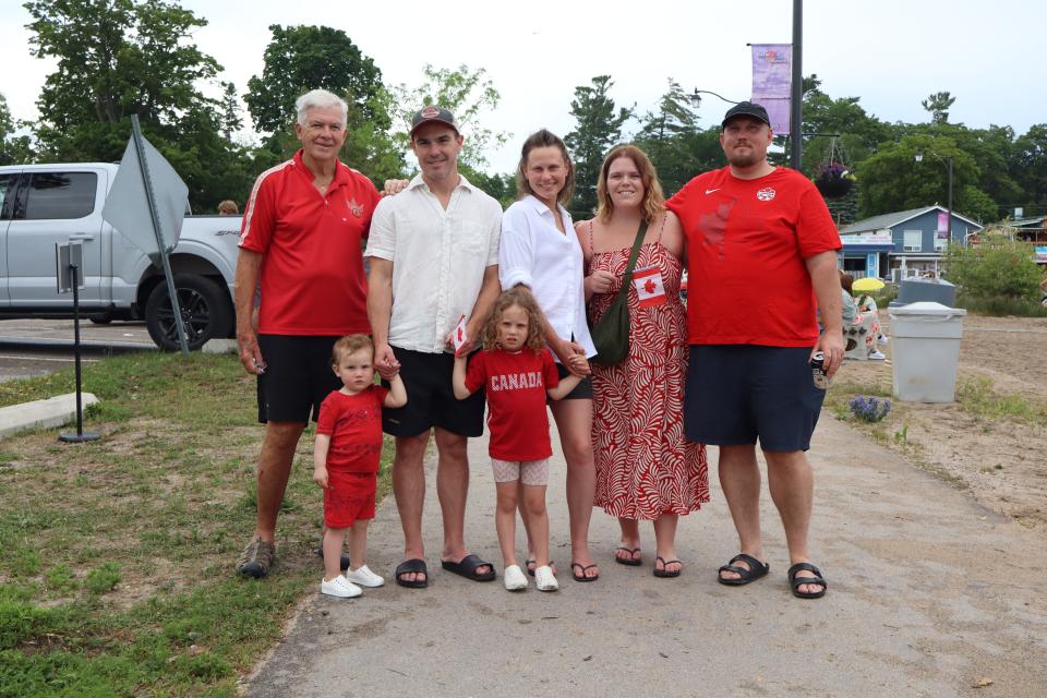 Large group of family/friends all dressed in red and white with two young children in the middle.