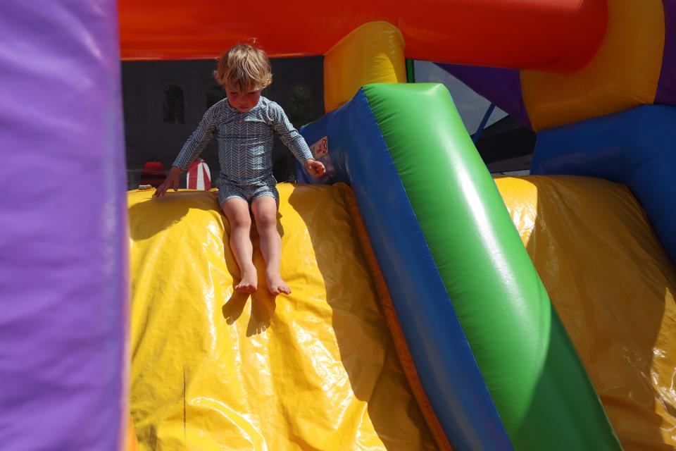 Child sliding down a brightly coloured bouncy castle on a sunny day.