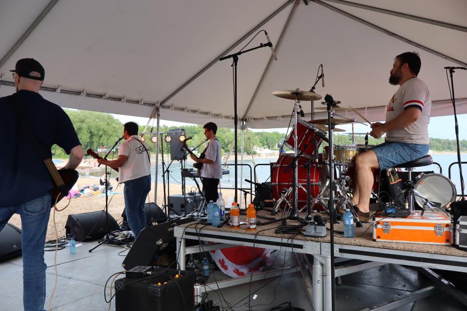 View from behind The Lonely Hearts band performing on stage looking out to the crowd.