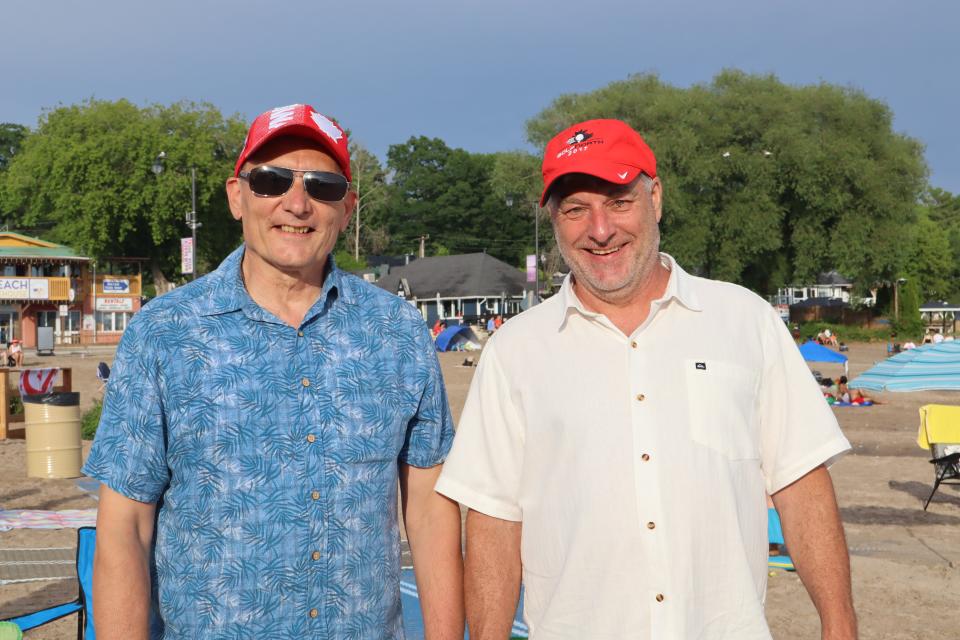 Councillor Brunelle and a man stand next to each other on the sand, their chairs set up to watch the entertainment.