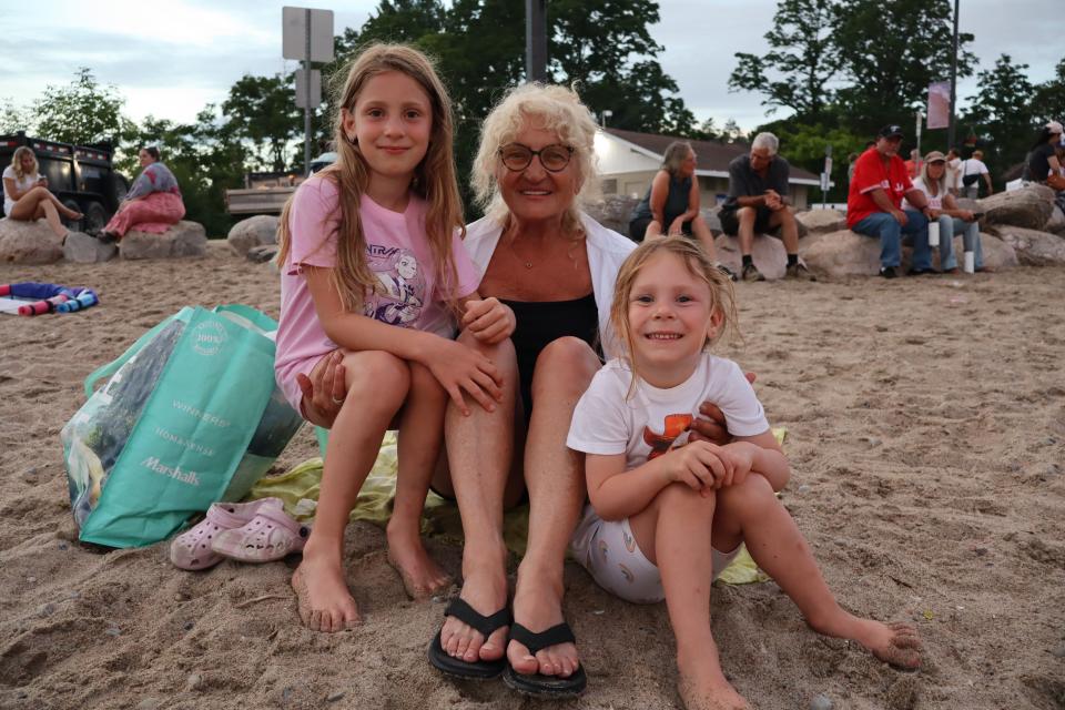 Grandmother with their two granddaughters sitting on the sand. 