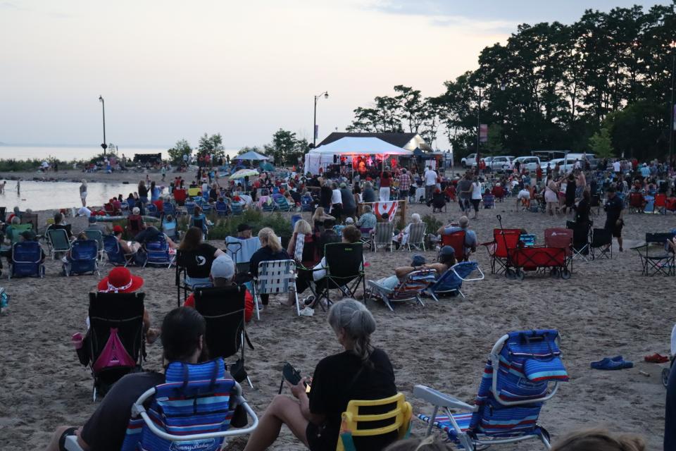 View from the back of the crowd gathering on sand enjoying the live entertainment.