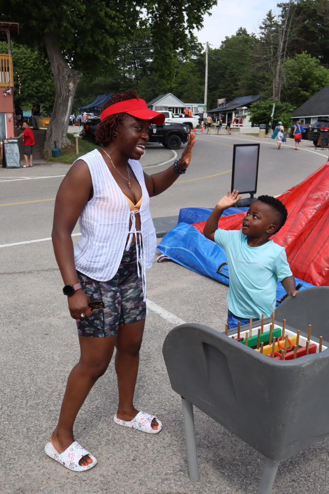 Mom and son about to high-five after playing with a ring toss game in the kids zone.