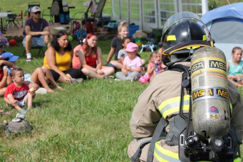 Township of Tiny Firefighter kneeling in front of a group of children