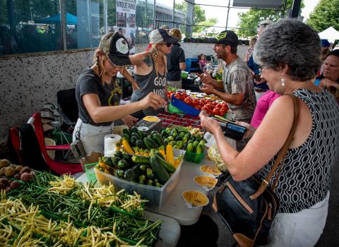 Vegetable vendor serves customer at vendor fair