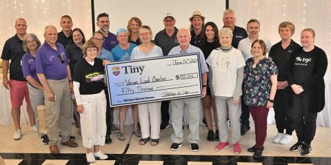 A group of people stand for a photo with a big cheque reading $50,000 for various local charities