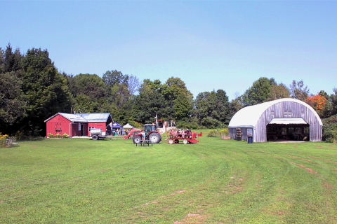 image of windlee farms from a distance with the farm buildings, farm crawl guests on a wagon ride, and blue skies