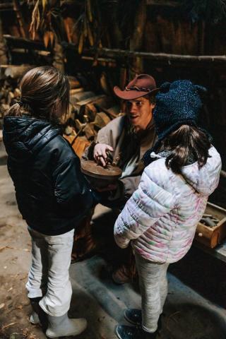 image of a man in costume showing two young girls an old tool