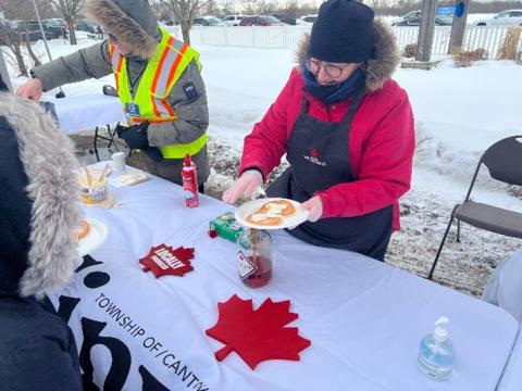 image of windlee maple farms putting maple syrup on a person's pancakes at the winter carnaval d'hiver