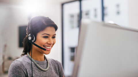 image of a woman using a headset in an office, sitting at a desk in front of a computer