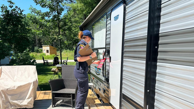 woman firefighter holding a checklist following up at a homeowner's front door