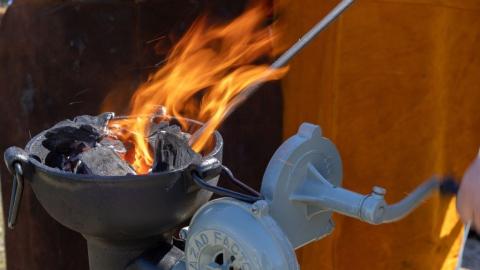 image includes a cropped view of a blacksmith's flame while they are forging a piece of steel