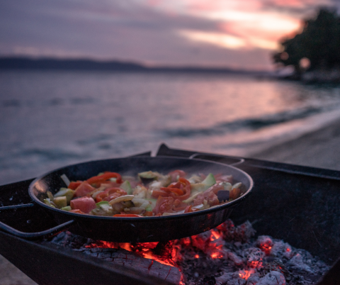 cast iron pan on a coals bbq on a beach at sunset