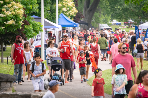 A crowd of people walking through a park on Canada Day