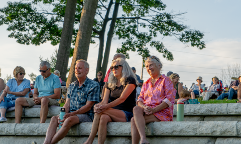 People sitting on stage seating in a park