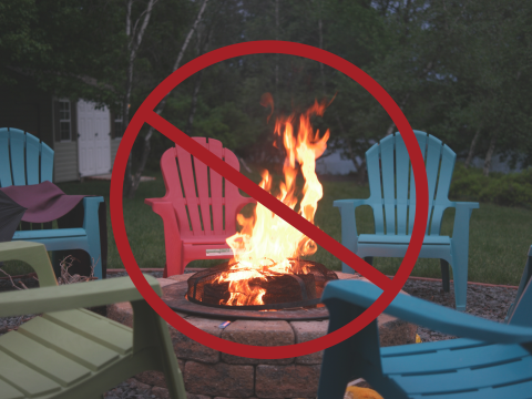 Large red prohibited sign on an image of a campfire with multiple coloured chairs