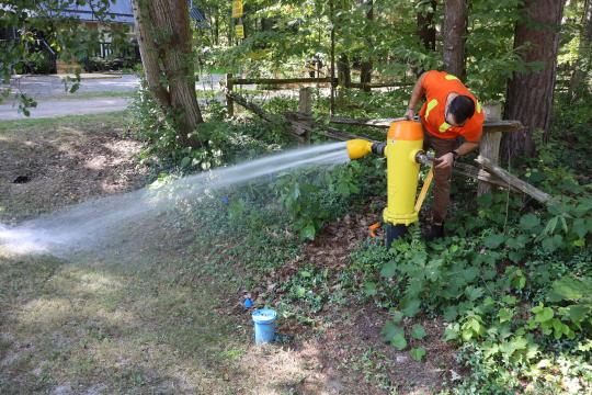 Township of Tiny water staff flushing a yellow and orange municipal hydrant