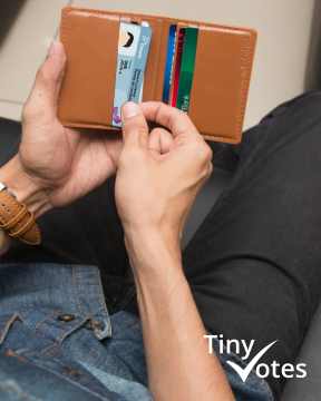 View from above a person's arms rested on their legs and torso pulling out their Ontario Driver's Licence from a brown leather wallet