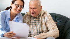 two adults looking at paperwork together on the couch
